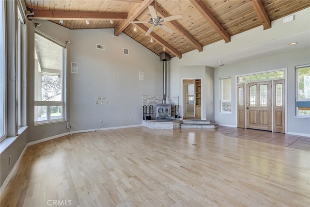 unfurnished living room with wood ceiling, a healthy amount of sunlight, light hardwood / wood-style flooring, and a wood stove
