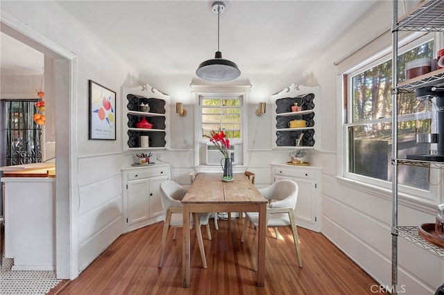 dining area with light wood-type flooring, plenty of natural light, and cooling unit