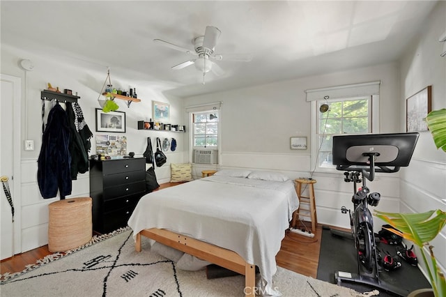 bedroom featuring wood-type flooring, multiple windows, ceiling fan, and cooling unit