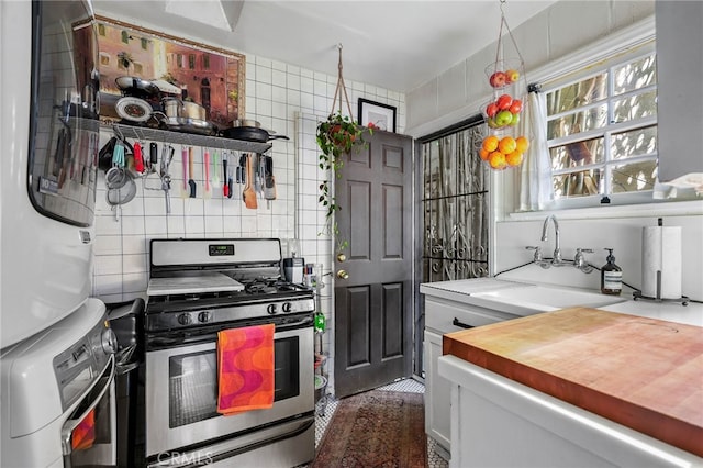 kitchen featuring white cabinets, gas range, sink, and decorative backsplash