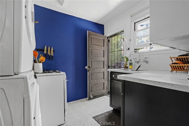 laundry room featuring stacked washer and dryer, sink, and cabinets