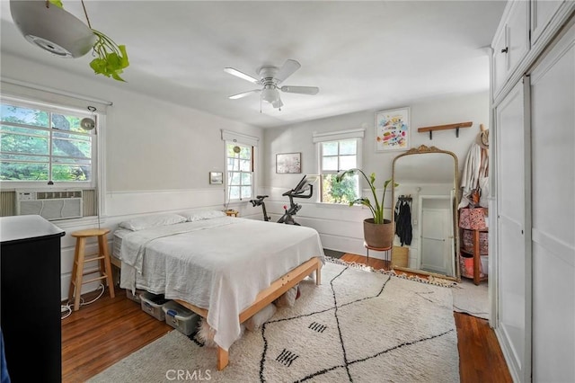 bedroom featuring dark hardwood / wood-style floors, cooling unit, and ceiling fan