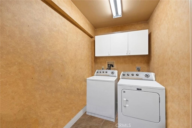 clothes washing area featuring washer and dryer, light tile patterned flooring, and cabinets