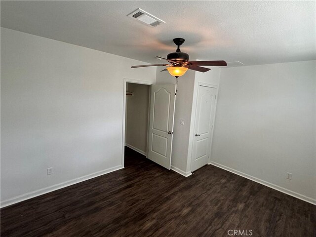 unfurnished bedroom featuring a textured ceiling, dark wood-type flooring, and ceiling fan