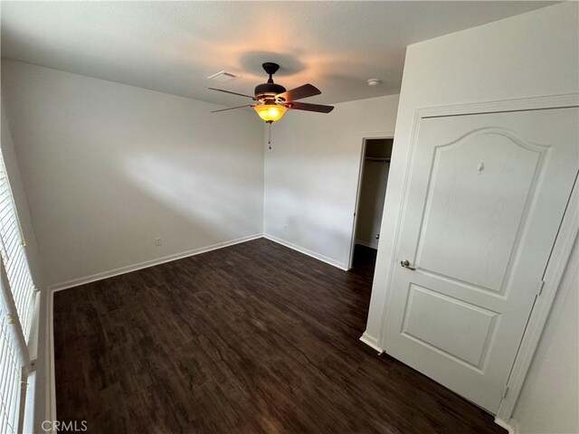 unfurnished bedroom with dark hardwood / wood-style flooring, a closet, and ceiling fan