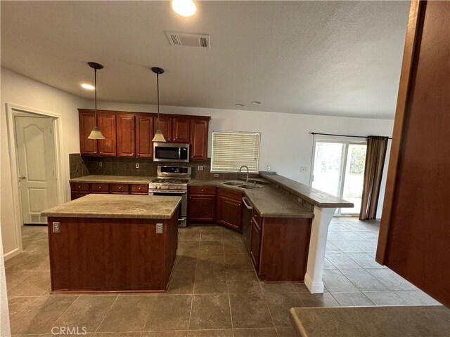 kitchen featuring decorative light fixtures, tasteful backsplash, sink, kitchen peninsula, and stainless steel appliances