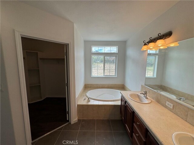 bathroom featuring vanity, tile patterned floors, and tiled bath