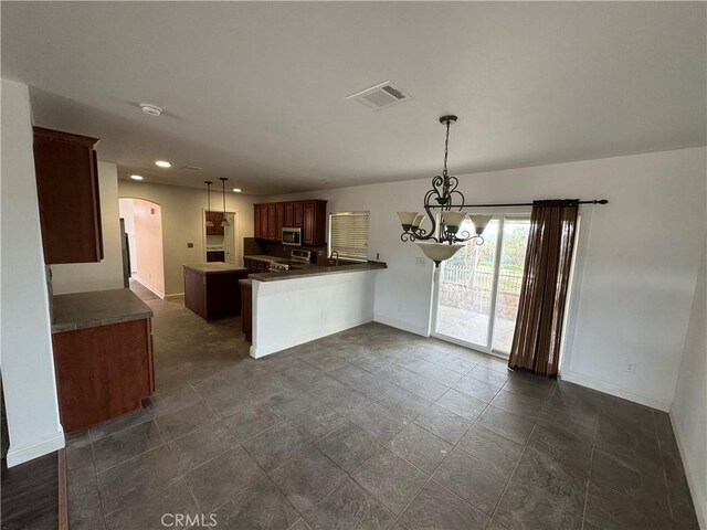 kitchen with pendant lighting, kitchen peninsula, a chandelier, and stove