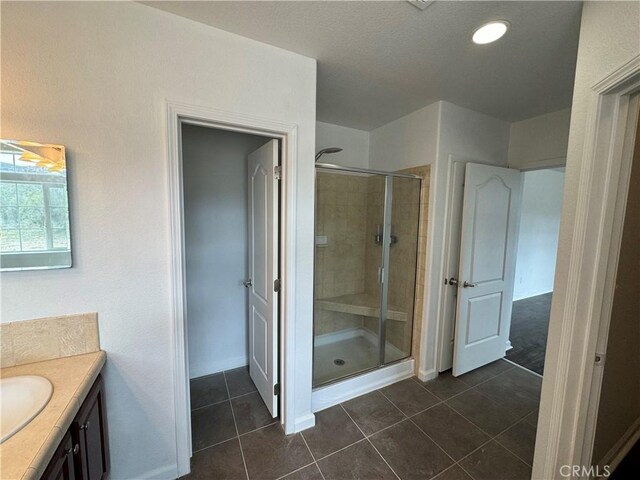 bathroom with an enclosed shower, vanity, and tile patterned floors