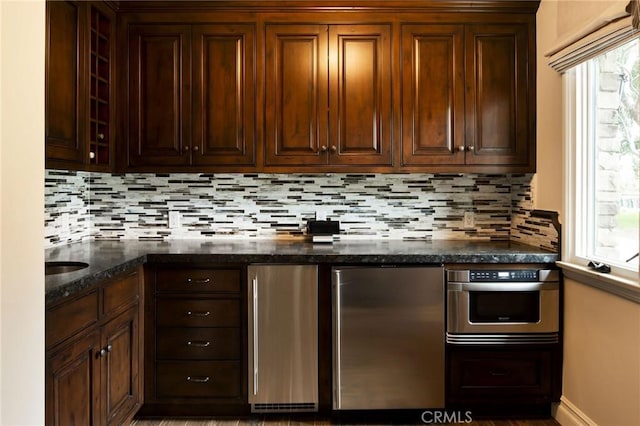 kitchen featuring decorative backsplash, dark stone counters, and appliances with stainless steel finishes