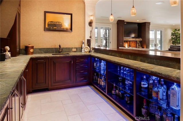 bar with stone counters, sink, and pendant lighting