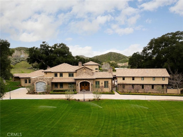 mediterranean / spanish-style home featuring a mountain view, a garage, and a front lawn