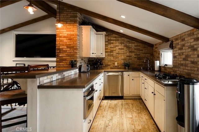 kitchen featuring light hardwood / wood-style flooring, vaulted ceiling with beams, appliances with stainless steel finishes, kitchen peninsula, and a breakfast bar area