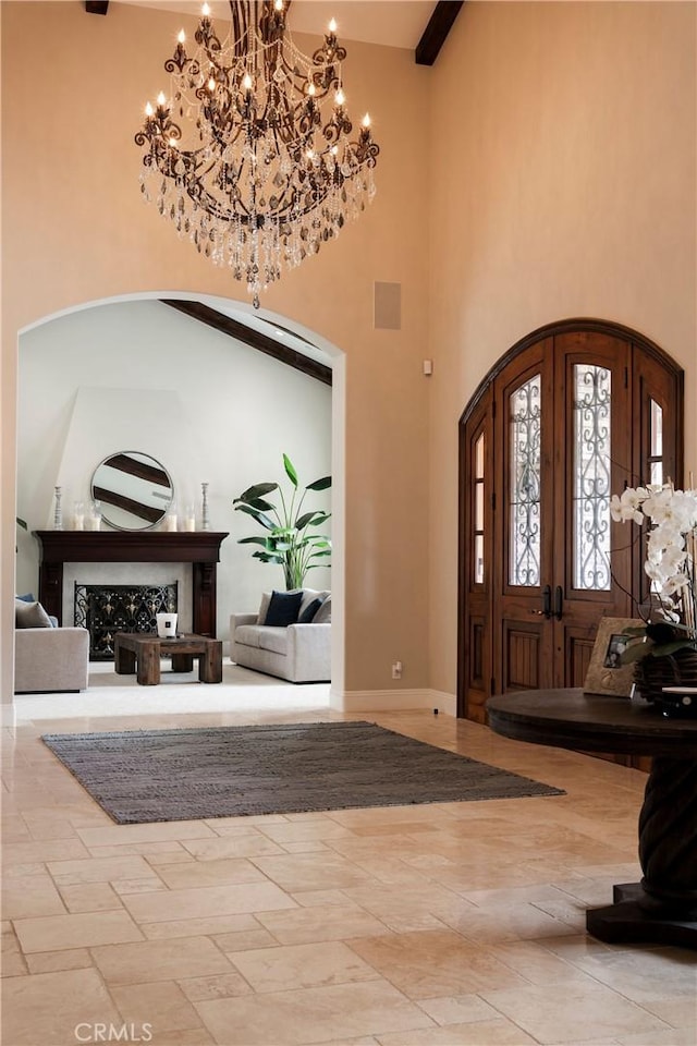 foyer featuring beamed ceiling, a notable chandelier, a fireplace, and high vaulted ceiling