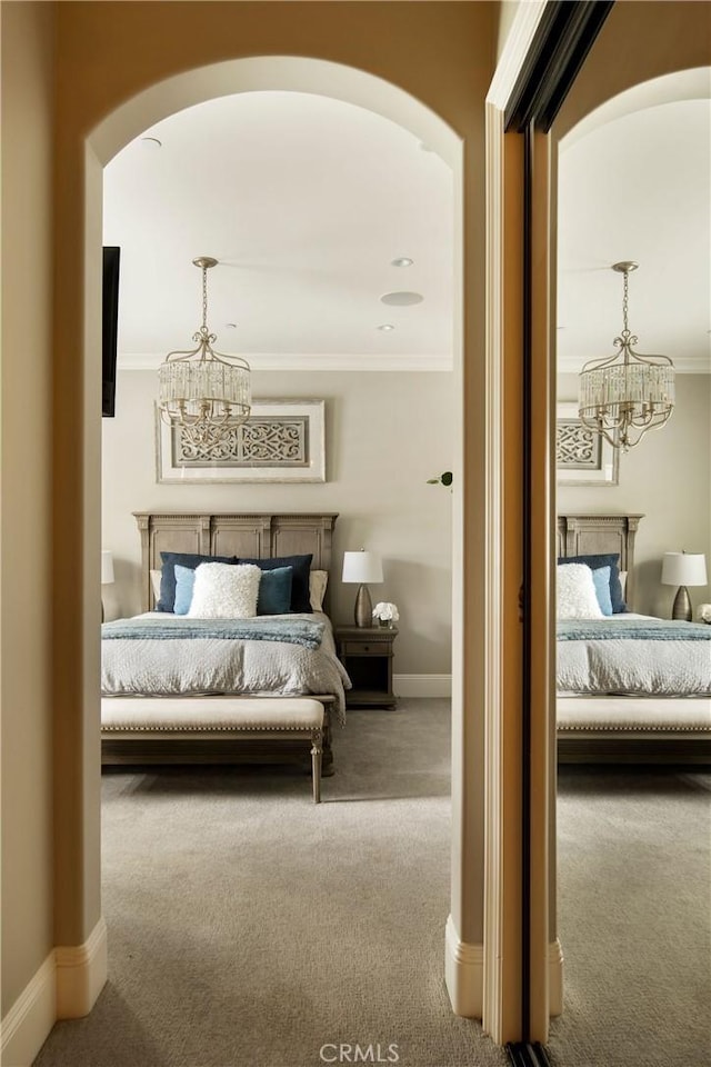 bedroom featuring carpet floors, crown molding, and an inviting chandelier