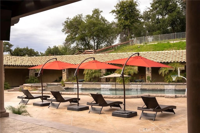 view of swimming pool with pool water feature and a hot tub