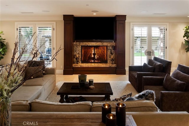 living room featuring a wealth of natural light, french doors, a high end fireplace, and crown molding