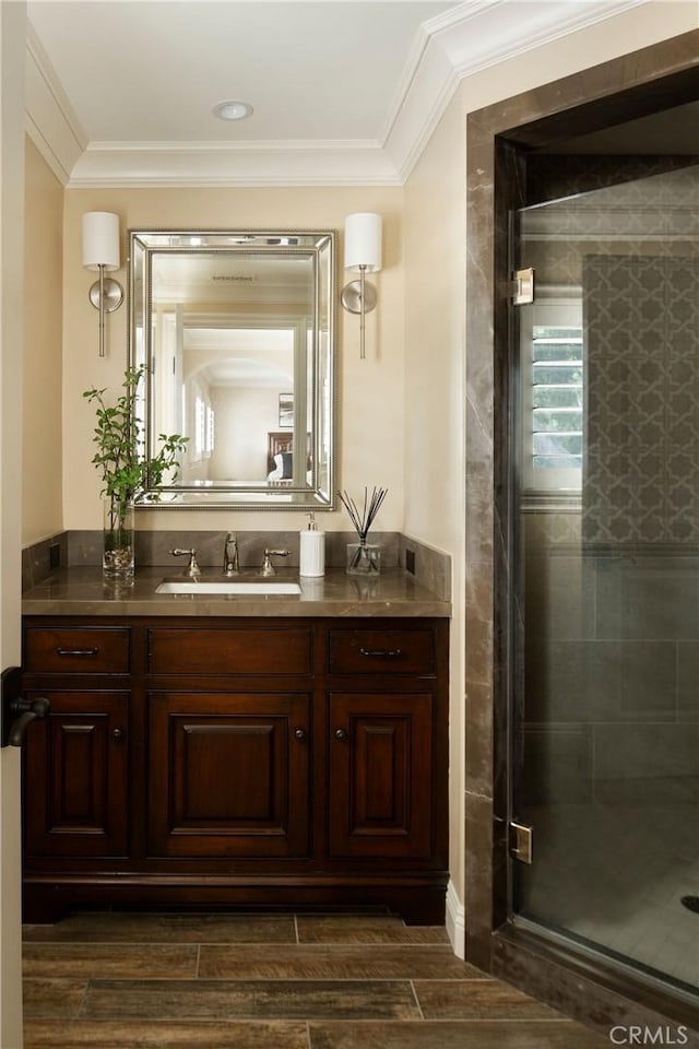 bathroom featuring wood-type flooring, vanity, a shower with shower door, and ornamental molding