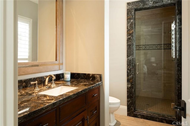 bathroom featuring hardwood / wood-style floors, vanity, toilet, and a shower with shower door