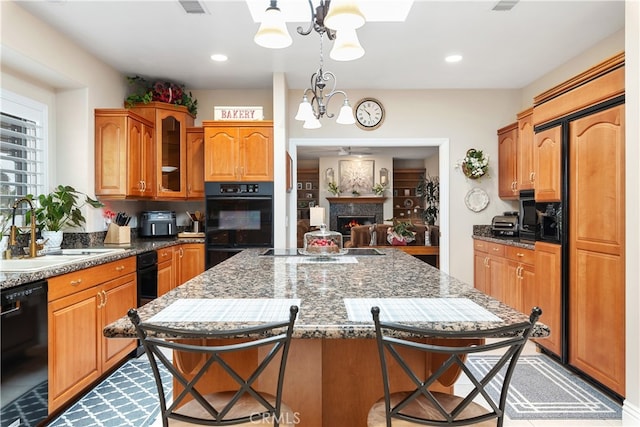 kitchen with pendant lighting, a chandelier, sink, a kitchen breakfast bar, and black appliances