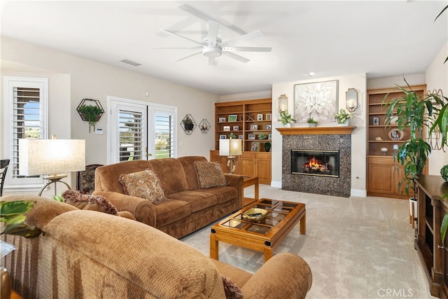 carpeted living room featuring ceiling fan and a tile fireplace