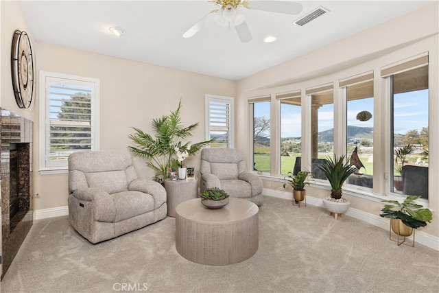 sitting room featuring ceiling fan, light colored carpet, and a fireplace