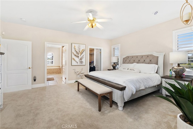 carpeted bedroom featuring ensuite bath, ceiling fan, a walk in closet, and a closet