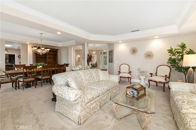 living room with an inviting chandelier, a tray ceiling, light carpet, and ornamental molding