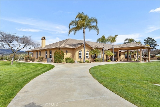 view of front of home featuring cooling unit, a front lawn, and a carport