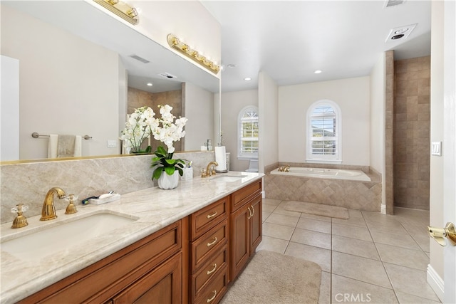 bathroom featuring tiled tub, vanity, tasteful backsplash, and tile patterned floors