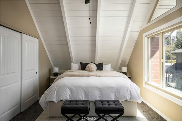 carpeted bedroom with multiple windows, a closet, and lofted ceiling with beams