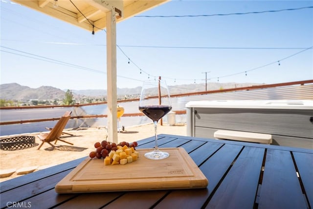 deck featuring a hot tub, a mountain view, and a fire pit