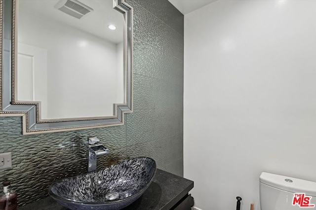 bathroom featuring tasteful backsplash, vanity with extensive cabinet space, and toilet