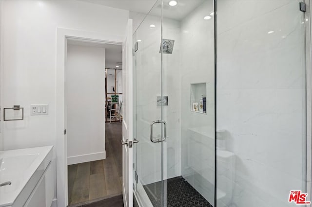 bathroom with a shower with shower door, vanity, and wood-type flooring