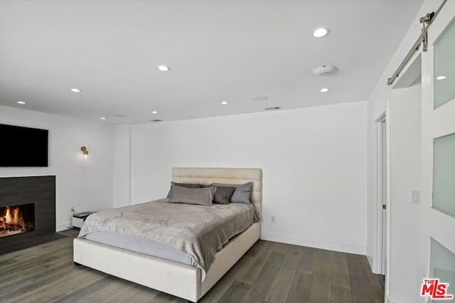 bedroom with dark hardwood / wood-style floors and a barn door