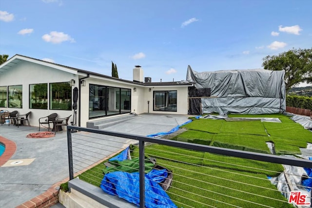 rear view of house featuring a lawn and a patio area