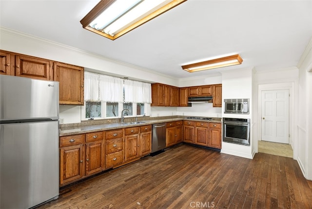 kitchen featuring light stone countertops, appliances with stainless steel finishes, dark wood-type flooring, ornamental molding, and sink