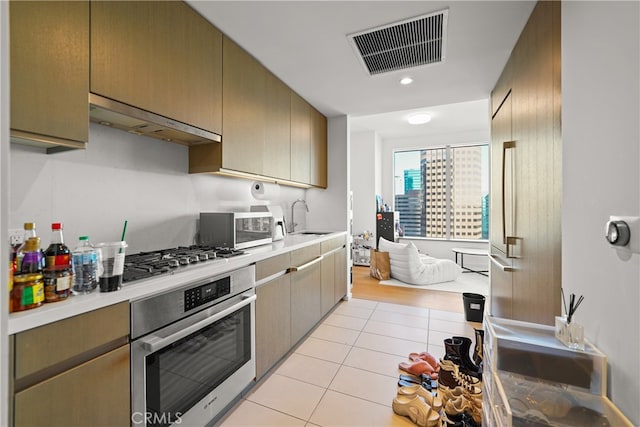 kitchen with extractor fan, appliances with stainless steel finishes, sink, and light tile patterned floors