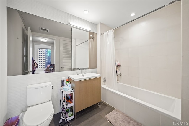 full bathroom with tile walls, shower / tub combo, vanity, and toilet