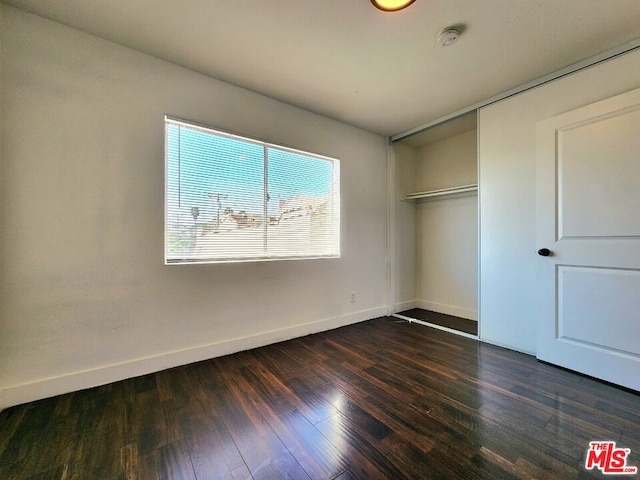 unfurnished bedroom with a closet and dark hardwood / wood-style flooring