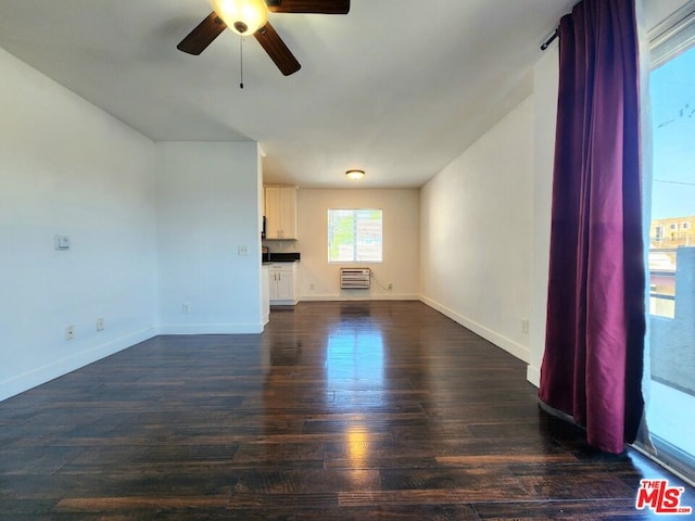 unfurnished living room with heating unit, ceiling fan, and dark wood-type flooring