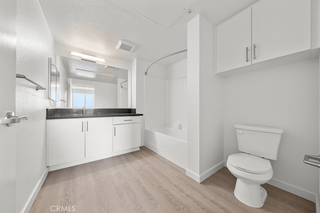 full bathroom with vanity, a textured ceiling, shower / bathtub combination, hardwood / wood-style flooring, and toilet