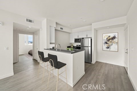 kitchen featuring kitchen peninsula, white cabinetry, light hardwood / wood-style flooring, appliances with stainless steel finishes, and a kitchen breakfast bar