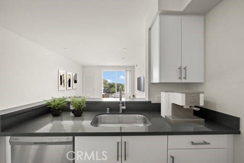 kitchen featuring sink, stainless steel dishwasher, and white cabinets