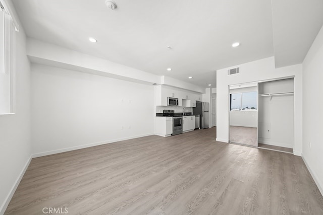 unfurnished living room with sink and light hardwood / wood-style floors