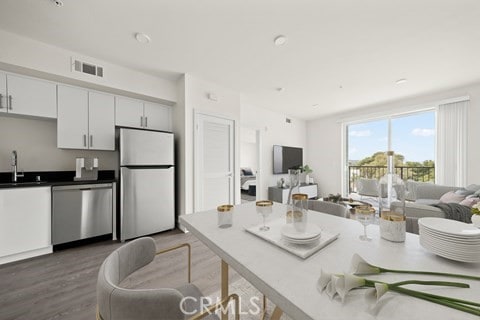 kitchen featuring appliances with stainless steel finishes, sink, dark hardwood / wood-style floors, and white cabinets