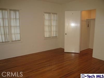 unfurnished bedroom with dark wood-type flooring and a closet