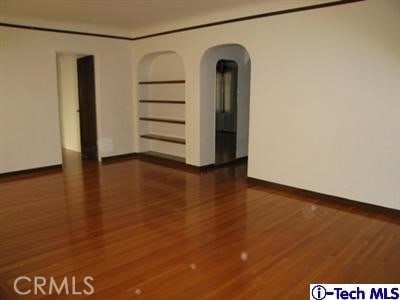 empty room with built in shelves and dark hardwood / wood-style floors