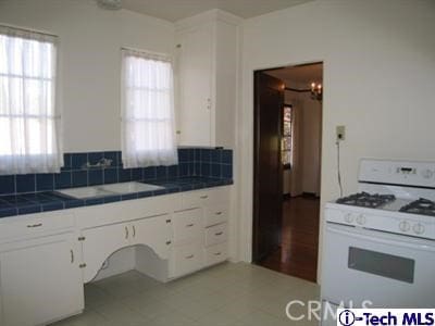 kitchen with white cabinets, a wealth of natural light, white gas stove, and tile counters