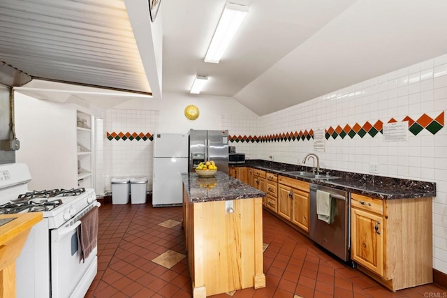 kitchen featuring a center island, appliances with stainless steel finishes, dark tile flooring, dark stone countertops, and sink